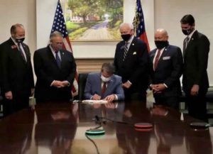 Georgia Gov. Brian Kemp signs voter restriction bill in front of painting of a plantation (Image: Twitter)