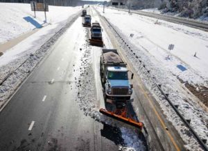 STAFFORD, VIRGINIA - JANUARY 04: Department of Transportation plow trucks scrape snow and ice off of a stretch of I-95 on January 04, 2022 between Fredericksberg and Stafford, Virginia. A winter storm with record snowfall slammed into the Mid-Atlantic states, stranding thousands of motorists overnight on 50 miles of I-95 in Virginia. (Photo by Chip Somodevilla/Getty Images)