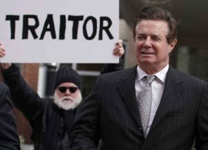ALEXANDRIA, VA - MARCH 08: Former Trump campaign manager Paul Manafort (R) arrives at the Albert V. Bryan U.S. Courthouse for an arraignment hearing as a protester holds up a sign March 8, 2018 in Alexandria, Virginia. Manafort was scheduled to enter a plea on new tax and fraud charges, brought by special counsel Robert Mueller's Russian interference investigation team, at the Alexandria federal court in Virginia, where he resides. (Photo by Alex Wong/Getty Images)