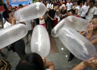 CHONGQING, CHINA - JULY 30: (CHINA OUT) People blow condoms during a blowing-condom match held by a condom brand to mark the upcoming Qixi Festival on July 30, 2006 in Chongqing Municipality, China. Qixi Festival, the Chinese equivalent of Valentine's Day, falls on the seventh night of the seventh lunar month on July 31. The festival originates from a romantic legend of lovers, the cowherd Niulang and fairy Zhinu, who were separated by the Supreme God. Story says that the couple reunites across the Milky Way once a year on the seventh day of the seventh lunar month. (Photo by China Photos/Getty Images)