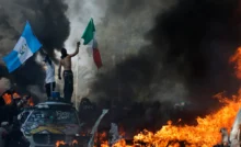 LOS ANGELES, CALIFORNIA - JUNE 08: Protestors wave flags as burning and vandalized Waymo cars line the street on June 08, 2025 in Los Angeles, California. Tensions in the city remain high after the Trump administration called in the National Guard against the wishes of city leaders following two days of clashes with police during a series of immigration raids. (Photo by Mario Tama/Getty Images)